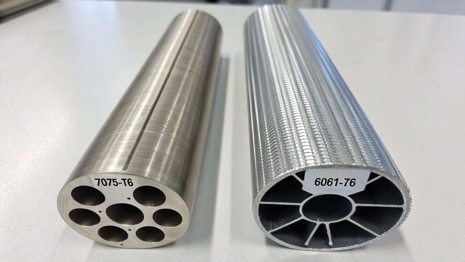 A rigid, machined 6061-T6 structural bracket next to a flexible, bent 5052 aluminum sheet metal enclosure.